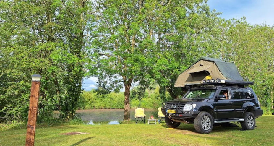 A roof tent pitched on the grass beside the lake