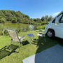 Chairs and a campervan beside the water